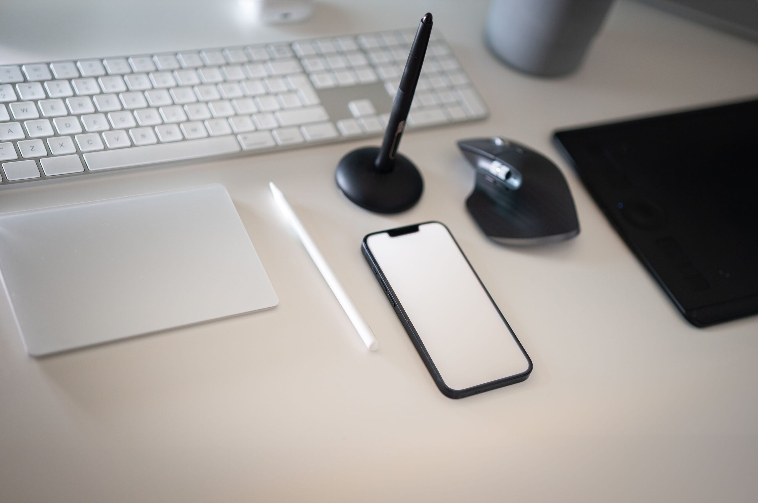 Clean and modern workspace featuring keyboard, smartphone, and wireless mouse with minimalistic design.
